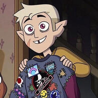 A screenshot from The Owl House. Hnter, a blonde boy with noticeable scars on his face, pointy ears one with a notch in it, and magenta eyes, is holding a shirt that is covered in numerous patches, he looks proud of himself